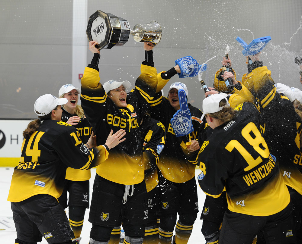 Kaleigh Fratkin is surrounded by Boston Pride teammates as she raises the Isobel Cup.  (Photo credit – Steve Babineau/Hockey Hall of Fame).